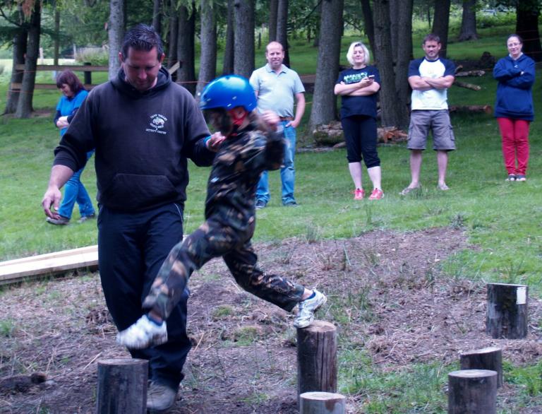 man holding young person who jumping over logs.