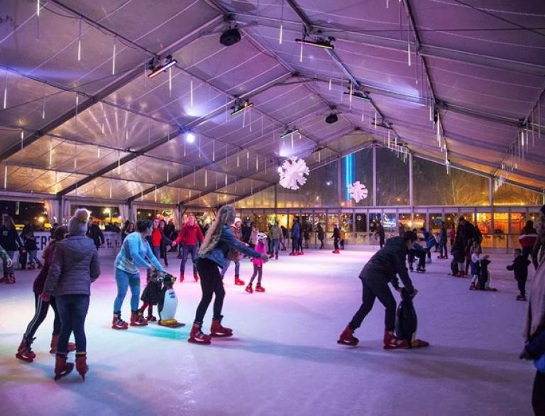 skaters on indoor skating rink with lights.