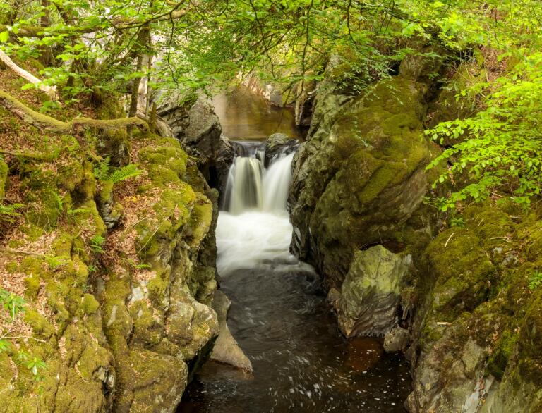 A waterfall flowing through a narrow ravine.