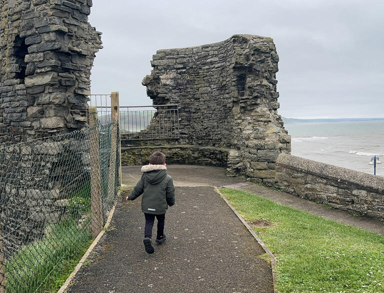 A young child exploring a ruined castle tower.
