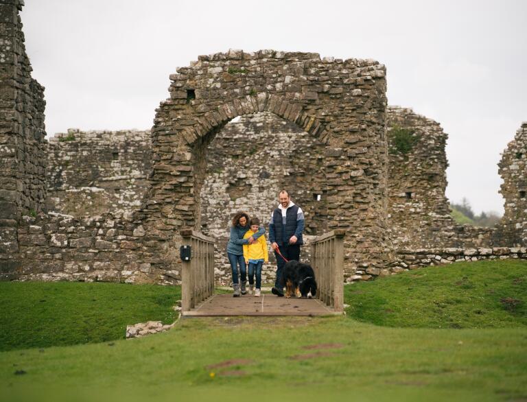 A family and a dog exploring a ruined castle. 