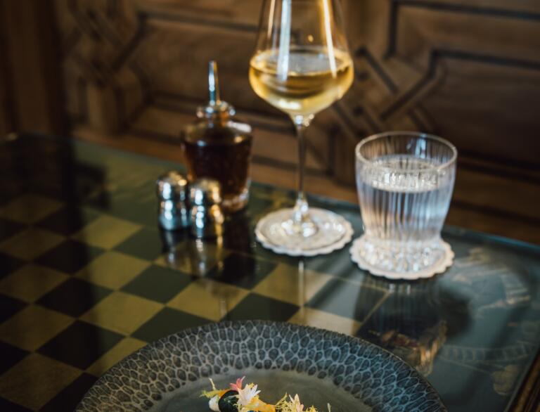 A plate of food beautifully presented, with wine and water glasses next to it.