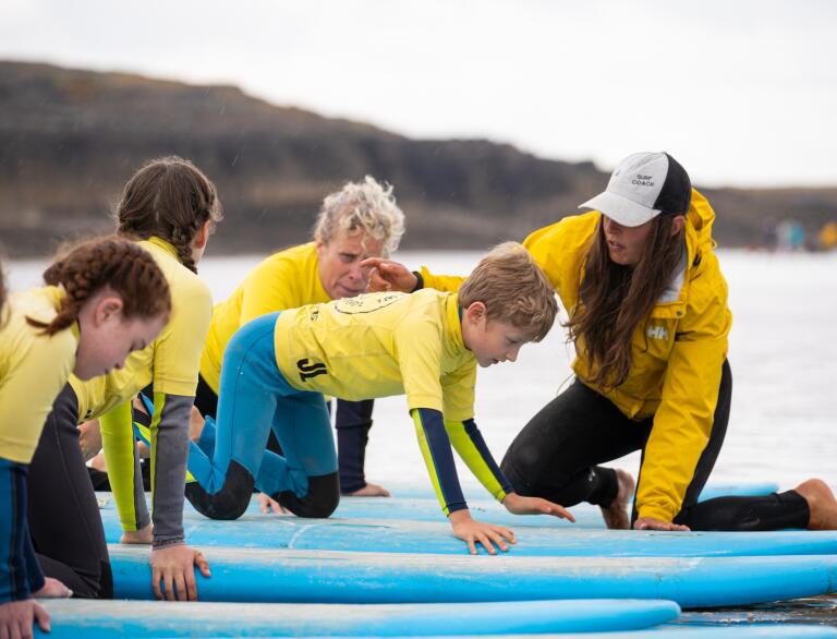 learner surfers on surf boards and instructor.