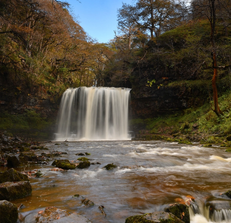 Sgwd yr Eira waterfall with trees in the background.