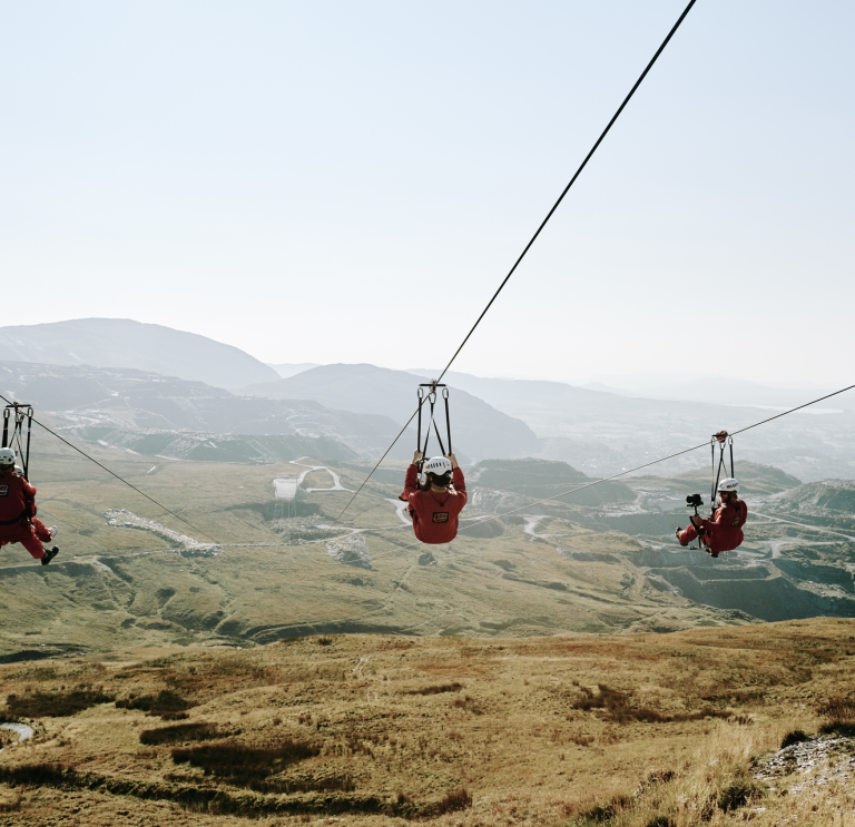 Individuals zip-lining above the mountains of Blaenau Ffestiniog. 