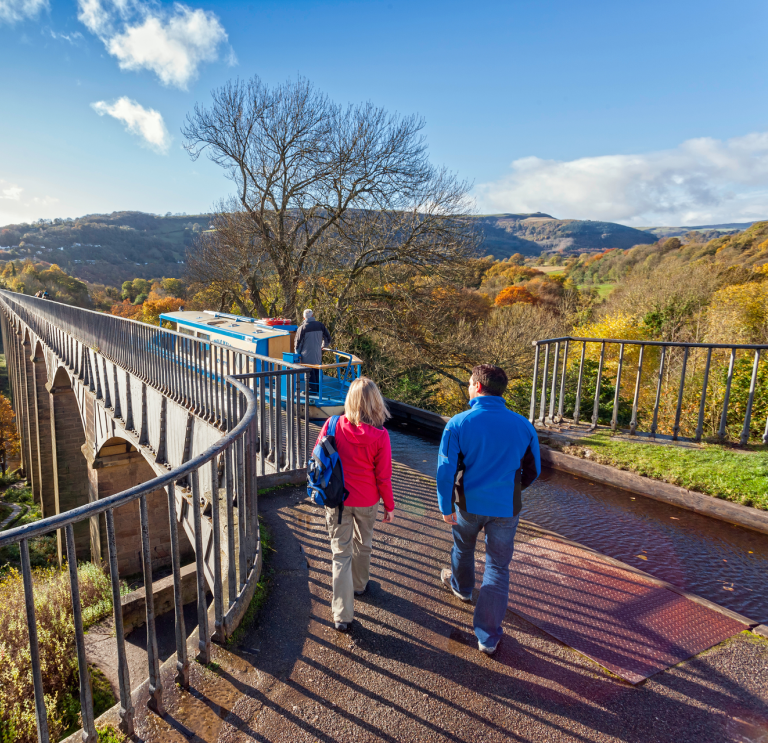 View of two people walking on the Pontcysyllte aqueduct in autumn.