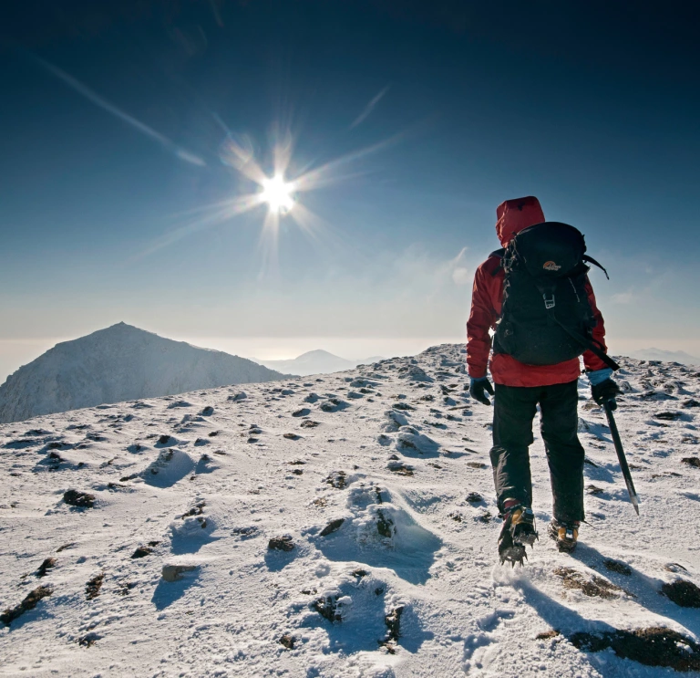 Walker / hiker / mountaineer approaching Snowdon summit in winter with heavy snow on ground