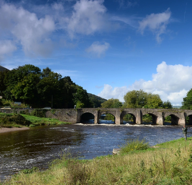 Man fishing in front of bridge over the River Usk, Abergavenny.