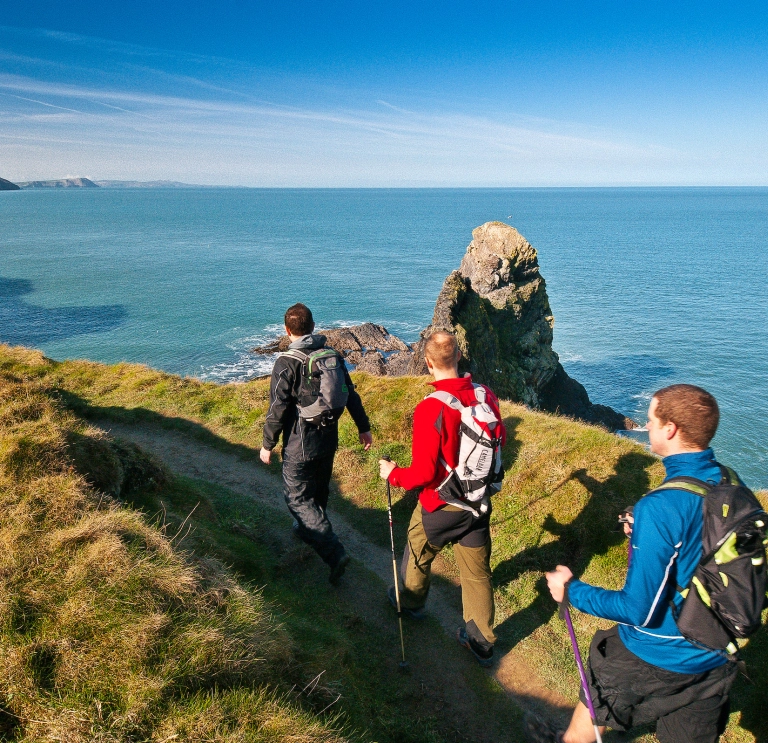 Three male walkers on Wales Coast Path, Pembrokeshire, West Wales