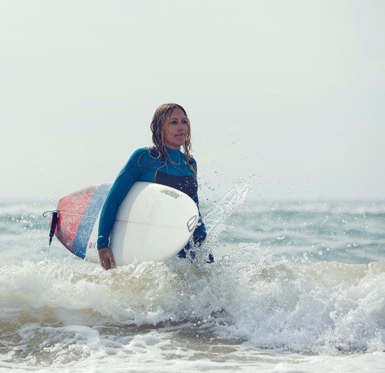 Kirsty Jones with surfboard in the sea
