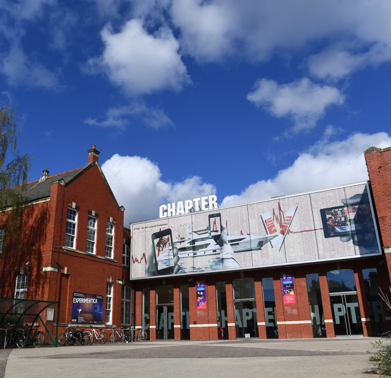 A red bricked old school building with a large hoarding over the entrance. 