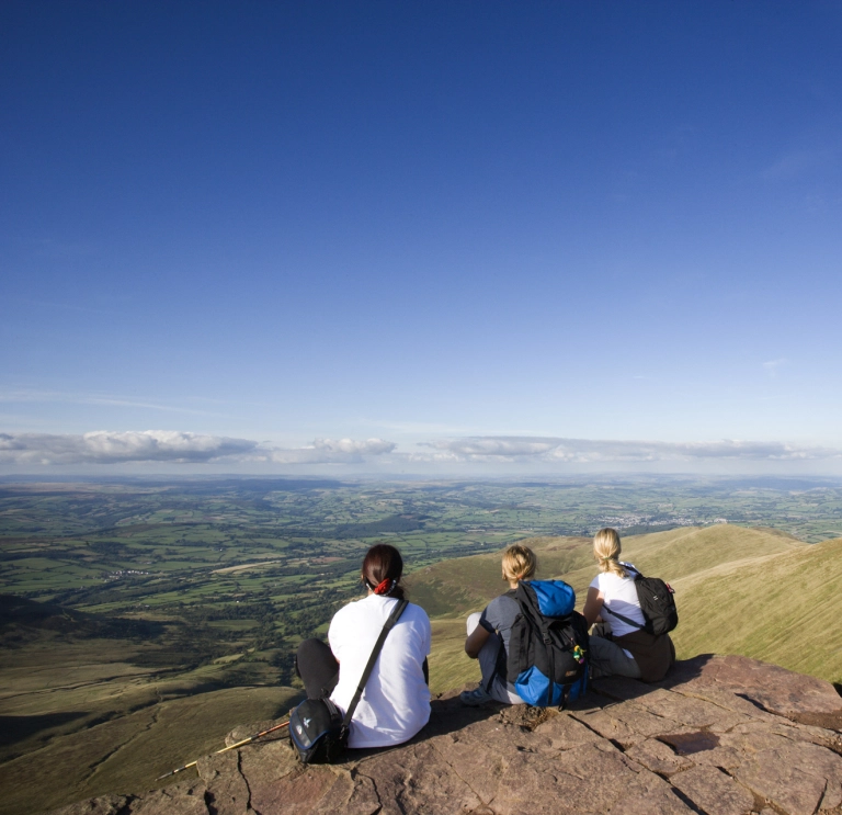 Walkers sat down overlooking mountains.