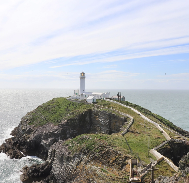 lighthouse on grassy outcrop.