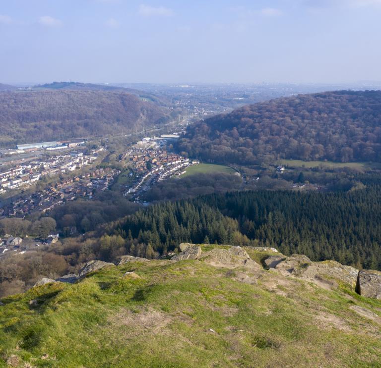 View from top of a mountain looking over houses and woodland.