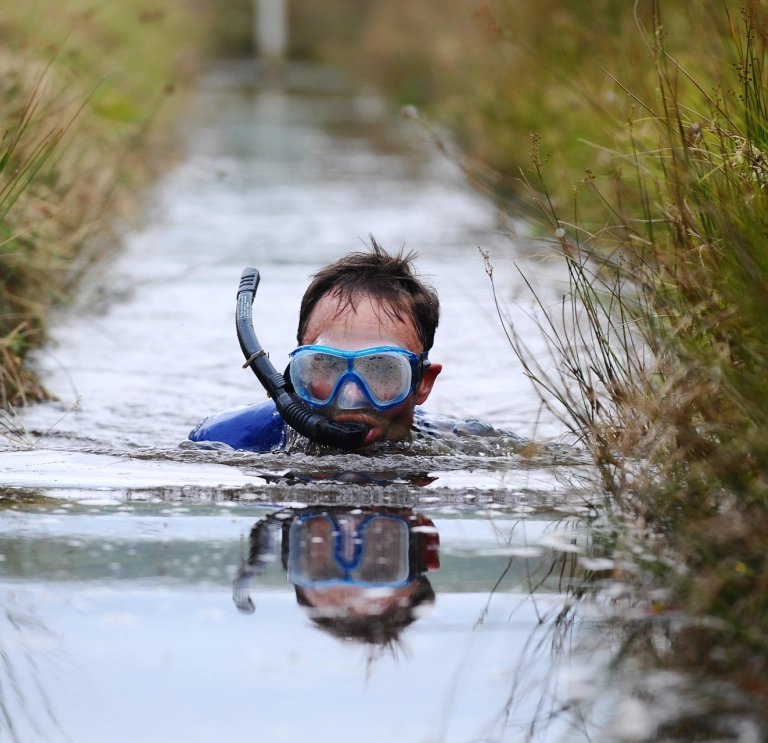 Image of a person wearing a snorkel and mask in a bog.