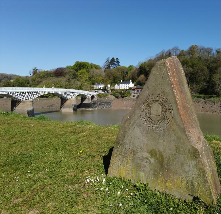A stone waymarker by a river.