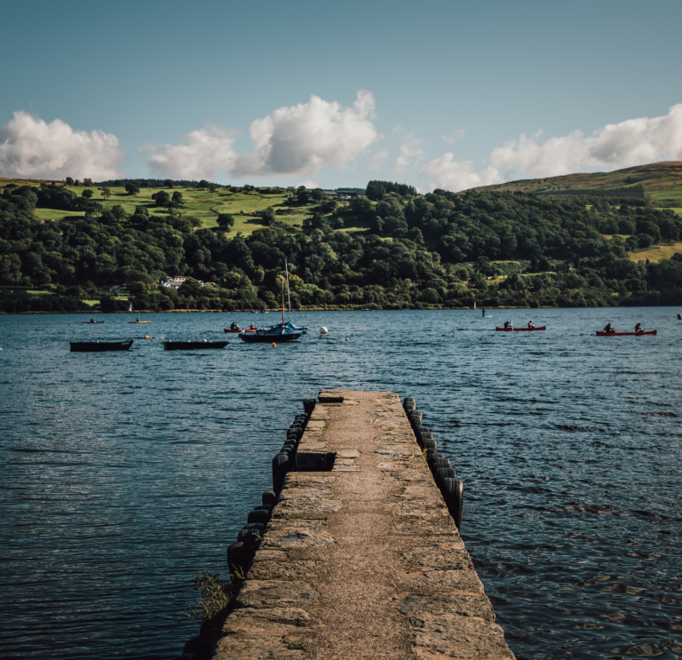 Lake with pontoon in foreground and boats and countryside in background.