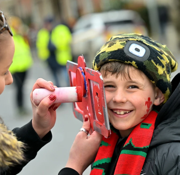 boy having stencil applied to his face.