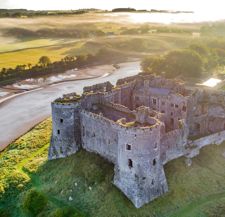 Luftaufnahme einer Burg mit umliegender Landschaft und Küste.