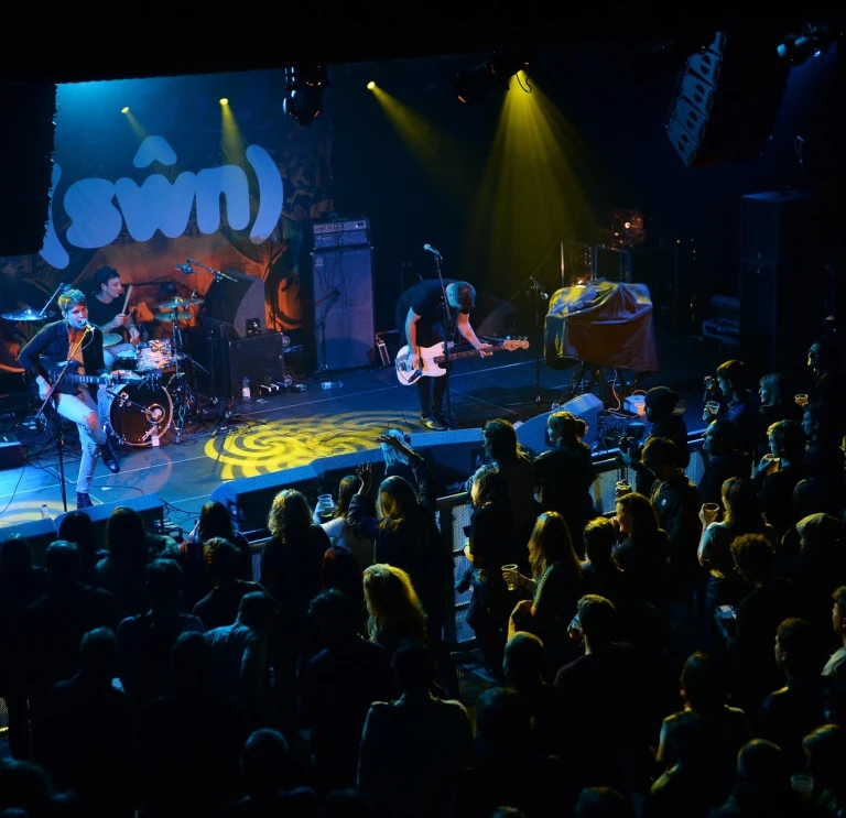 A band on a stage with a drummer and two guitarists.