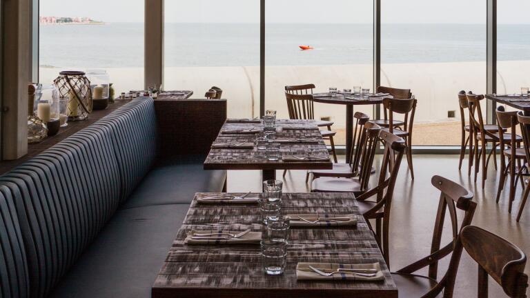 Interior of a restaurant, with view of sea.