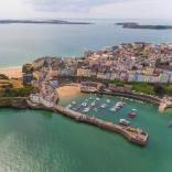 An aerial shot of a pretty harbour town with beaches, a castle, harbour and lifeboat station.