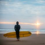 Mann am Strand von Wales mit Blick aufs Meer bei untergehender Sonne