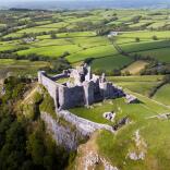 Aerial view of a castle on a hill in the middle of green fields.