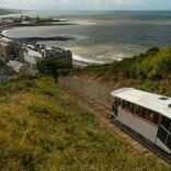 View from a hillside of a cliff railway and a seaside resort with a pier.