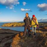 Couple walking above Porth Wen at sunset near Amlwch on the Wales Coast Path.