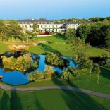 A hotel with a beautiful lake and grounds in front.