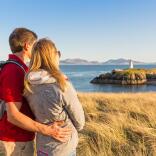 Couple looking out over beach and lighthouse.