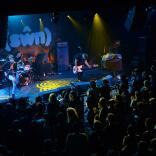 A band on a stage with a drummer and two guitarists.