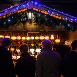 nighttime shot of Christmas market stall selling lamps with people in the foreground.