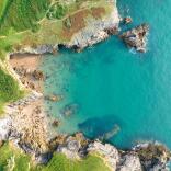 aerial view of sandy beach, green pathways and clear blue sea.