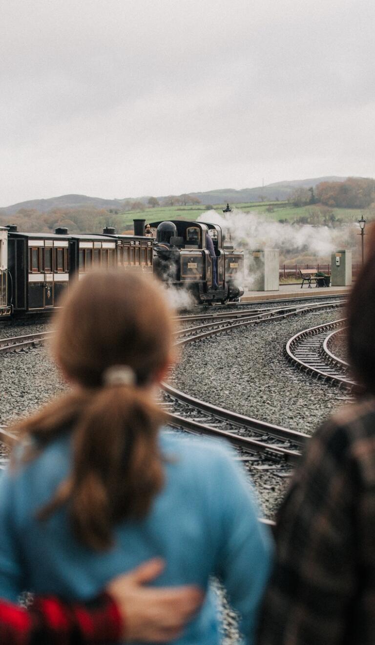 three people looking at a steam train.
