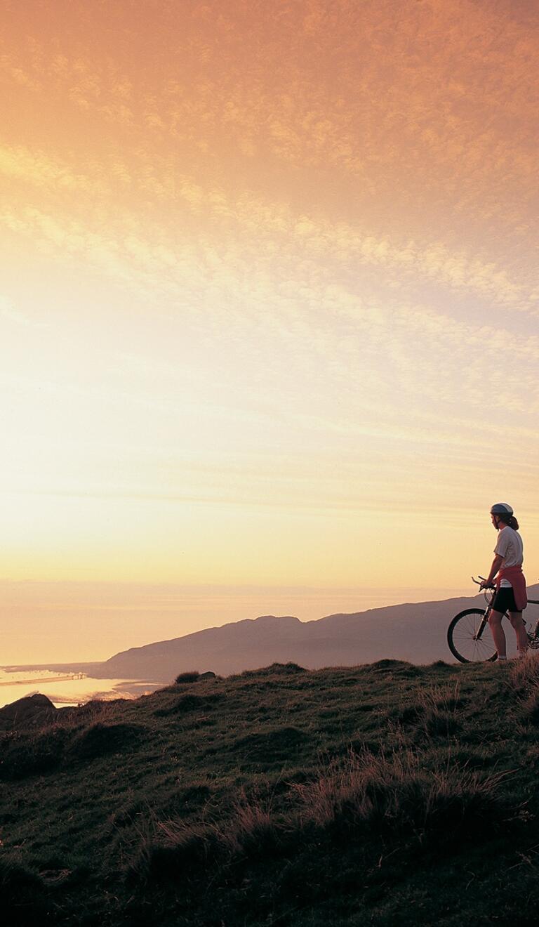 Two mountain bikers watching a sunset over the Mawddach eastuary.